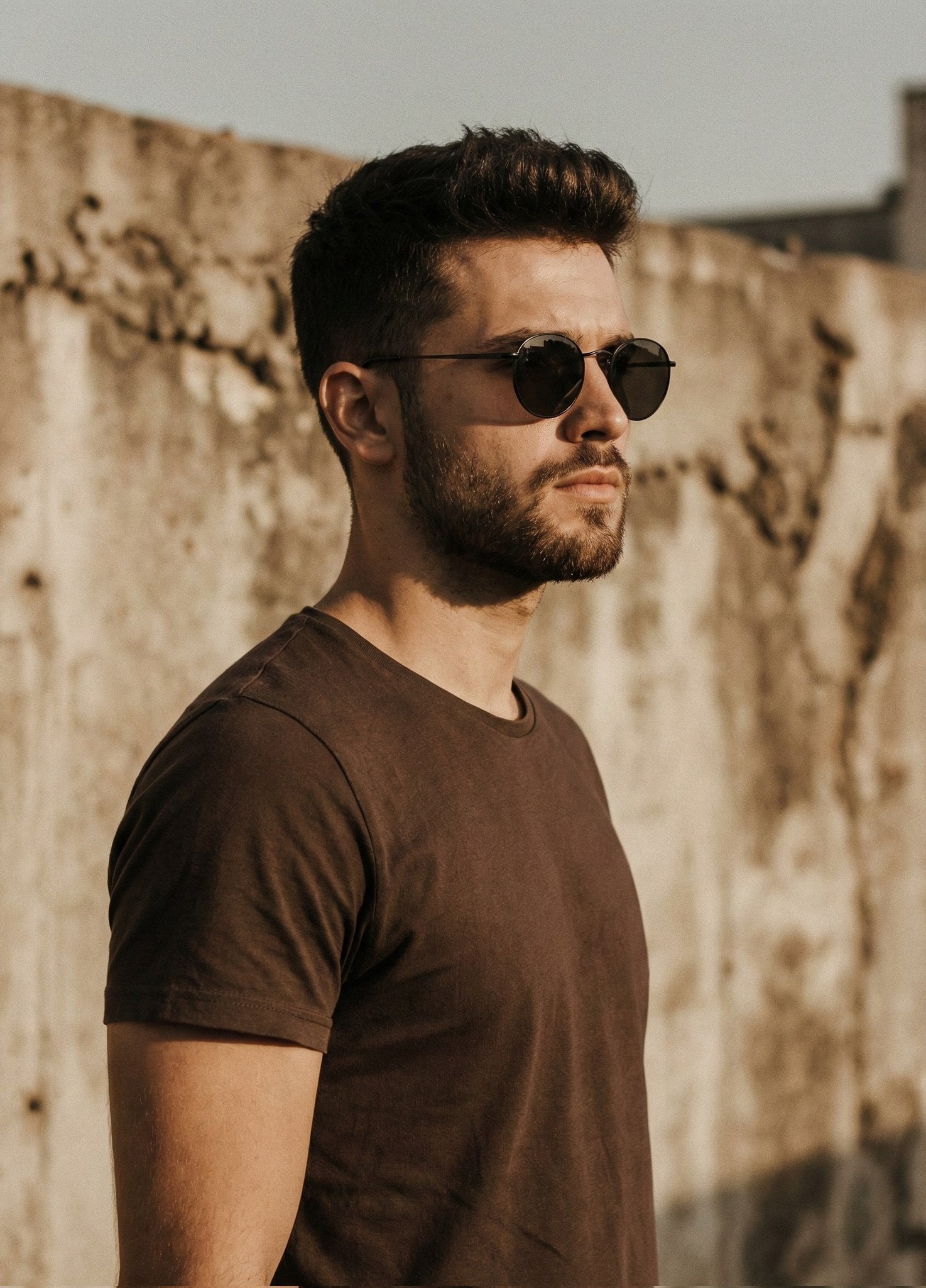 A cinematic portrait of a handsome man with a short styled haircut and trimmed beard, wea...