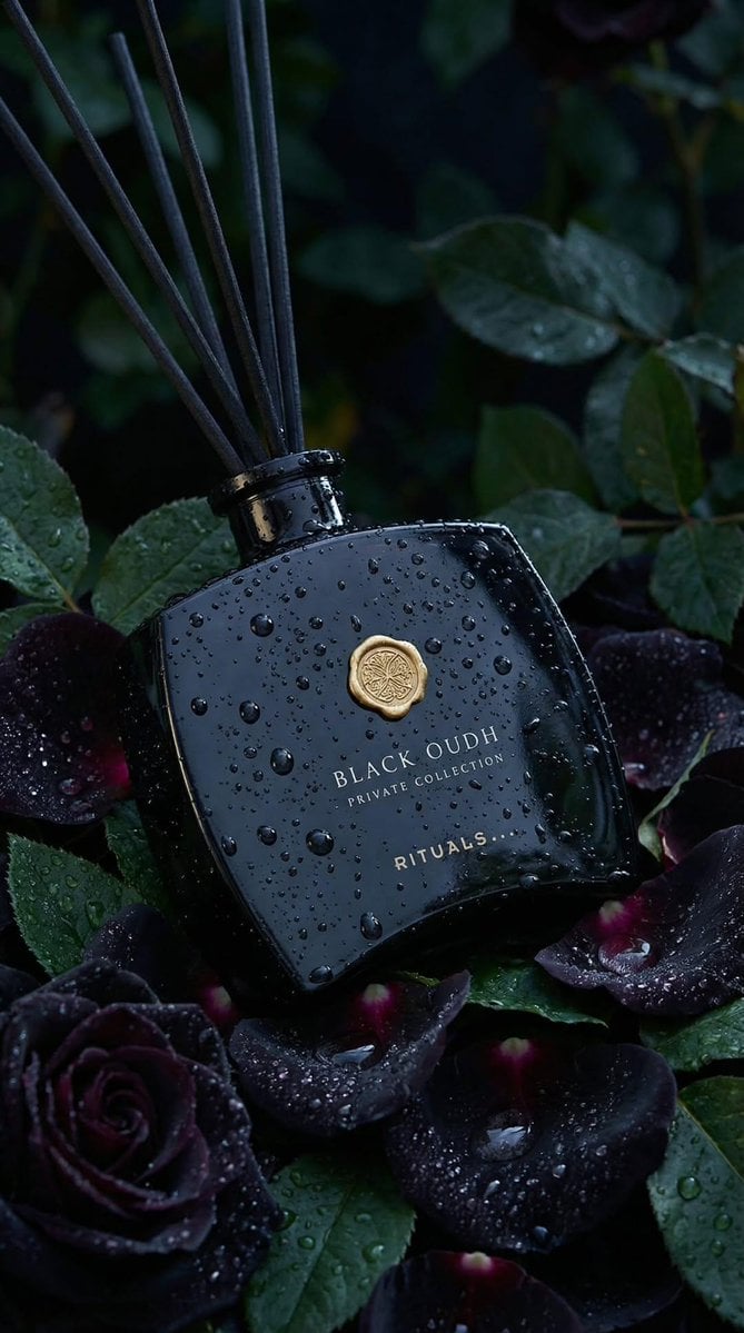 Ultra-realistic luxury product photography of a black glass reed diffuser bottle labeled ...